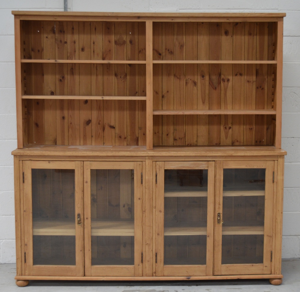 A pine dresser, the later bordered rack with adjustable shelves above four glazed doors,
