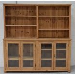 A pine dresser, the later bordered rack with adjustable shelves above four glazed doors,