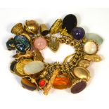A 9ct gold charm bracelet with over thirty gold and yellow metal charms to include a small globe,