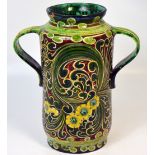 A Della Robbia twin handled waisted cylindrical vase, green ground with yellow decoration,