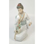 A large Nao model of a kneeling geisha girl tending to her flowers, height 34cm.