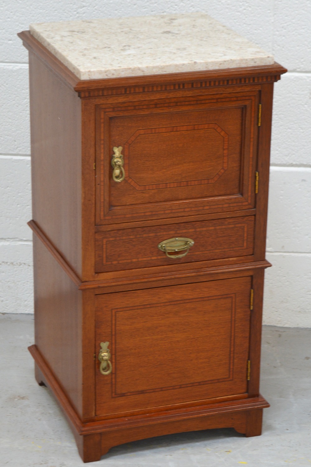 A mid 20th century mahogany and inlaid bedside cabinet, the marble top above cupboard door,