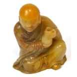 A Chinese carved soapstone figure of a seated gentleman holding a vase and wearing a robe, height 6.