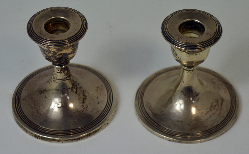A pair of George V hallmarked silver loaded candlesticks, Birmingham 1919, height of both 10cm.