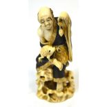 A Japanese Meiji period carved ivory okimono depicting a gentleman wearing textured robes with a