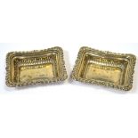A pair of Edwardian hallmarked silver pin dishes of rounded rectangular form with floral scrolling