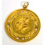 A 14ct gold circular pendant with floral decoration to one side and Chinese characters to the