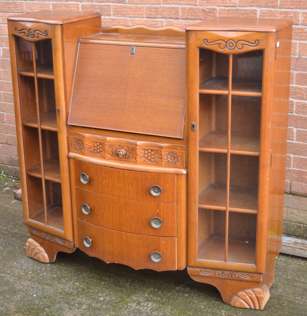 An oak display cabinet/bureau with four central drawers on moulded feet, width 121cm.