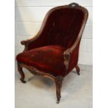 A Victorian walnut carved low nursing chair on castors.