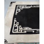 An Oriental wool black ground rug with ivory border and ivory Oriental design to each corner,