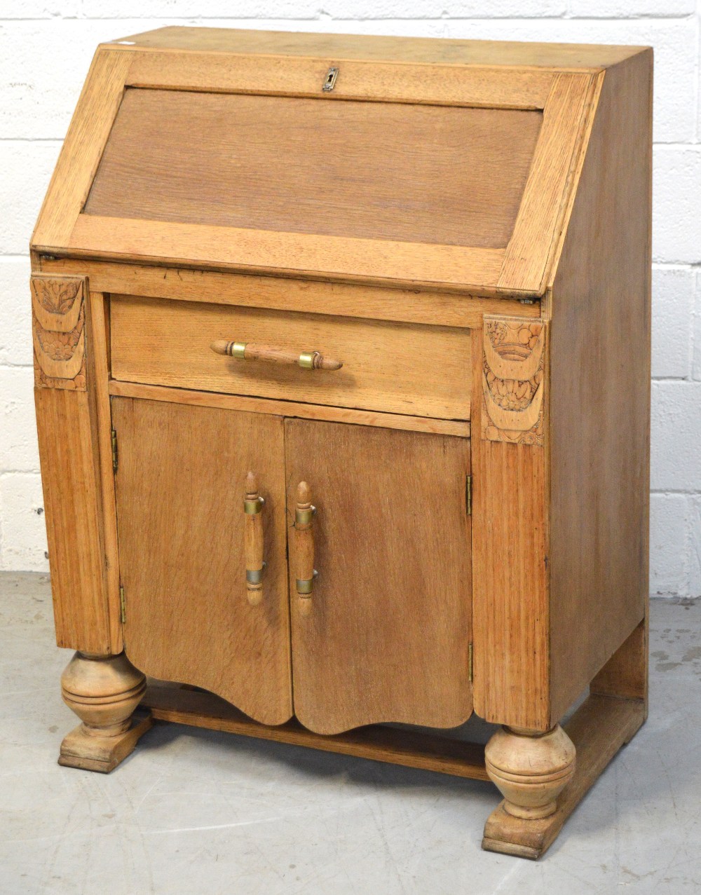 A mid 20th century oak bureau with interior pigeon holes and drawer above one drawer and two