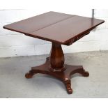 A mahogany fold-out card table, raised on central turned baluster column and quadripartite base,