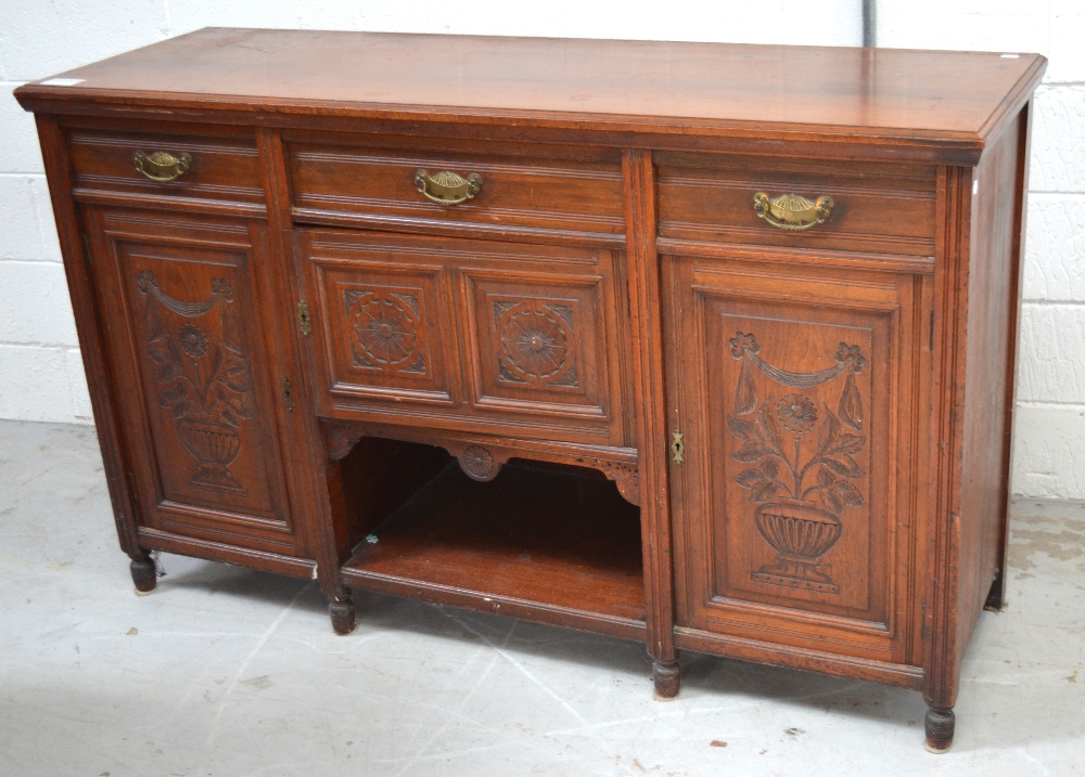 An early 20th century mahogany sideboard with carved urn and swag decoration to panelled doors,