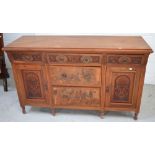 A 20th century walnut sideboard with three central drawers and two heavily carved cupboard doors to