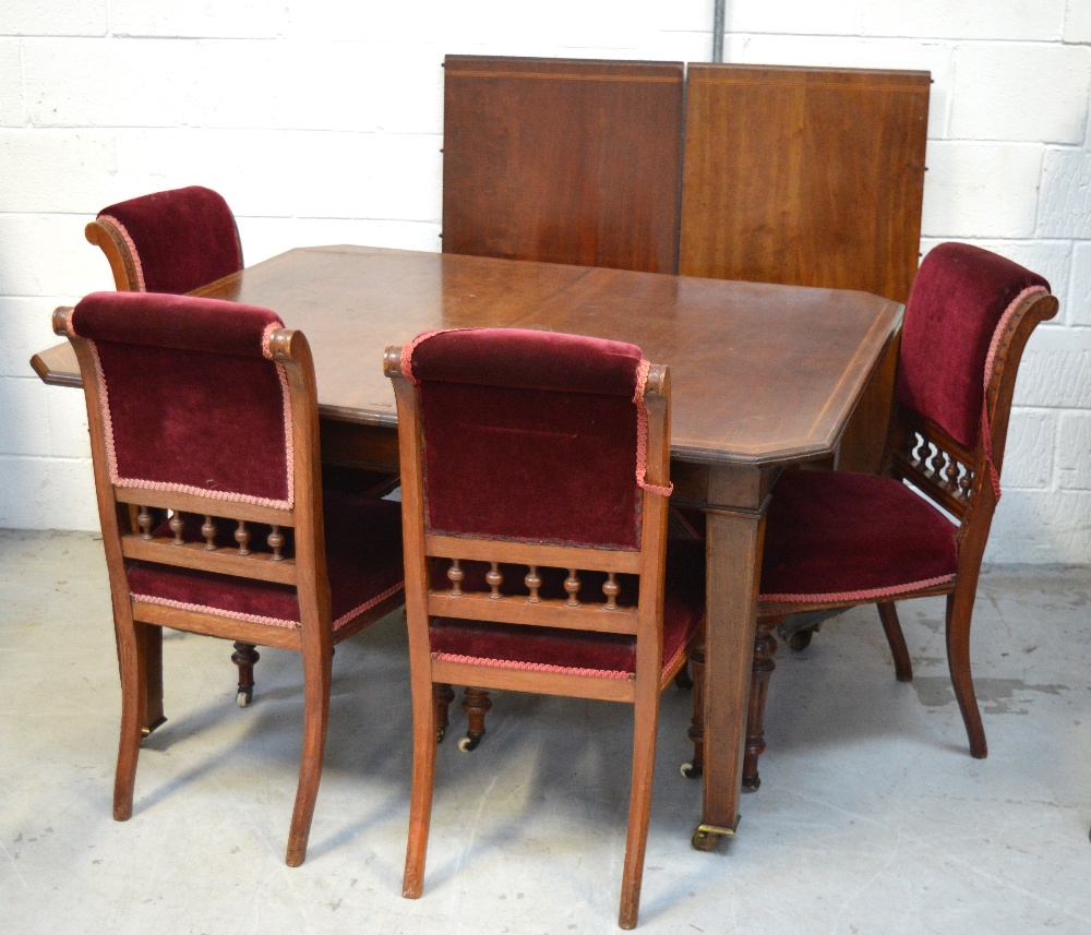 An Edwardian mahogany and inlaid extending dining table on castors,