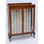 A walnut bowfronted display cabinet with two glazed doors above squat cabriole feet,