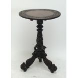 An Indian carved wooden circular table with central column and tripod base with outswept legs