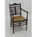 An Edwardian mahogany carved elbow chair with foliate scroll motifs to back and embroidered seat on