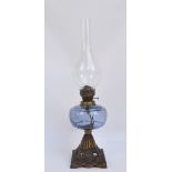 A late Victorian cast iron oil lamp with blue glass reservoir above tapering square floral