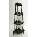 A reproduction carved mahogany bowfront four tier whatnot decorated with floral motifs,