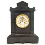 A late 19th century French black slate mantel clock with white enamel dial showing exposed