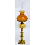 A late Victorian oil lamp with pale peach tinted reservoir, etched shade, and brass column,