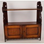 An Edwardian walnut wall unit with two shelves above a pair of doors with fretwork to the sides,