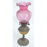 A Victorian oil lamp with brass gadrooned reservoir above similarly decorated spreading circular