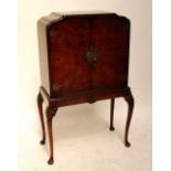 A 1940s walnut cocktail cabinet with two shaped doors above a base raised on knee carved cabriole