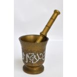 An early 20th century turned bronze pestle and mortar with overall incised decoration and copper