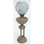 A Victorian oil lamp with brass reservoir raised on three columns above circular stepped base,