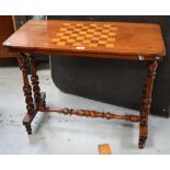 A Victorian walnut games table with central turned stretcher and supports, width 83cm.