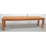 A long rectangular pitch pine dining table on block supports,