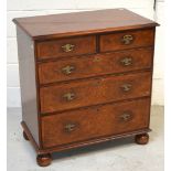 A two-over-three walnut chest of drawers on bun feet, width 80cm.