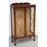 An Edwardian mahogany display cabinet with twin astragal glazed doors on cabriole supports,