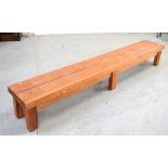 A pitch pine long low rectangular table/bench on block supports, 254 x 40cm.