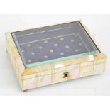 A mother of pearl faced trinket box with bevelled glass to the hinged lid enclosing a quilted
