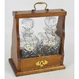 An oak tantalus housing two clear glass decanters,