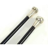 An ebonised walking cane with hallmarked silver mounted knob and worn bright cut decoration,