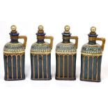 A set of four Doulton Lambeth stoneware decanters, each with a silver plated cork stopper,