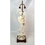 A large Chinese blanc de Chine standing Guanyin figure raised on a naturalistic lotus form base,