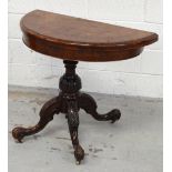 A Victorian walnut demi-lune fold-over card table, raised on carved quadripartite base and castors,