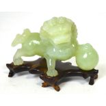 A Chinese pale green jadeite model of a chi-chi with front paw raised upon a sphere set on a shaped