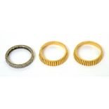 A ring trio to include two yellow metal rings with ribbed design and a central white metal ring set