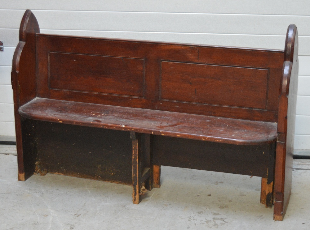 A stained pitch pine church pew of traditional form with panelled back, length 149cm.