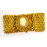 A yellow metal wide link bracelet with central cameo fastening in a floral and foliate frame,