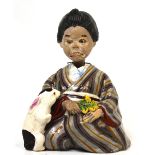 A Japanese pottery figure of a seated nodding lady holding flowers with a rabbit at her knee,