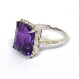 A 14ct white gold ring set with an emerald cut purple amethyst within a border of diamonds,