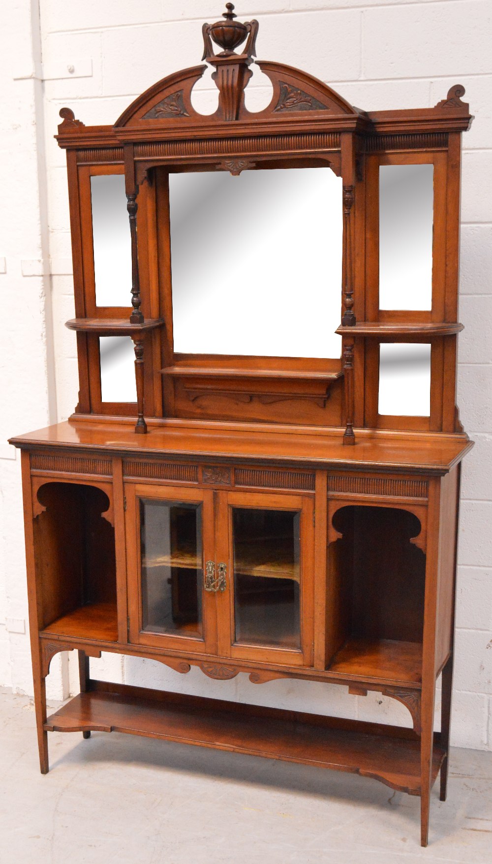 An early 20th century walnut display cabinet, urn carved pediment above four bevel edge plates,