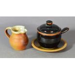 Winchcombe Pottery; a stoneware lidded soup bowl with saucer and a small jug,